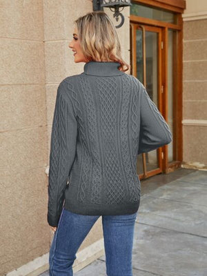 Back view of a woman wearing a gray cable-knit mock neck sweater paired with jeans.