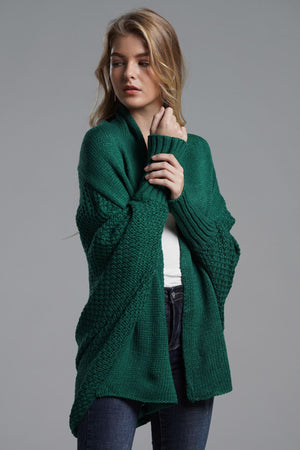 Model wearing a chic green dolman sleeve open front cardigan with ribbed details in a studio setting.