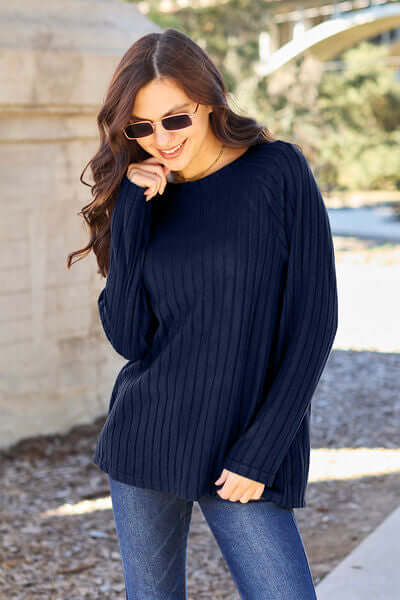 Model wearing a navy ribbed round neck long sleeve knit top with sunglasses in an outdoor setting.