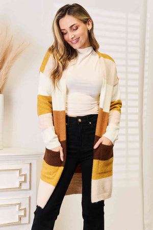 Color block dropped shoulder cardigan in warm shades with pockets, styled over a top and black jeans.