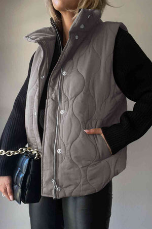 Collared neck vest with pockets in grey, featuring a quilted design and worn over a black sweater.