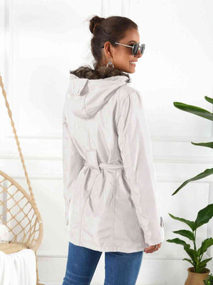 Woman wearing a full size hooded jacket with detachable liner, showcasing its stylish back view.