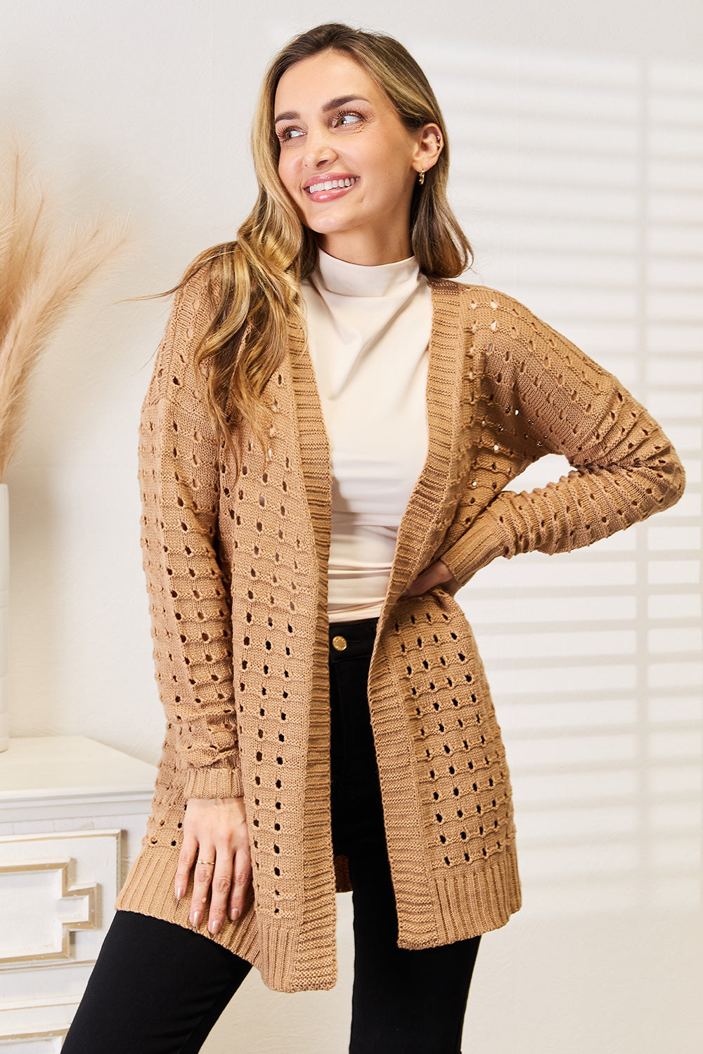Woman modeling a beige openwork ribbed open front cardigan, showcasing its elegant design and layering versatility.