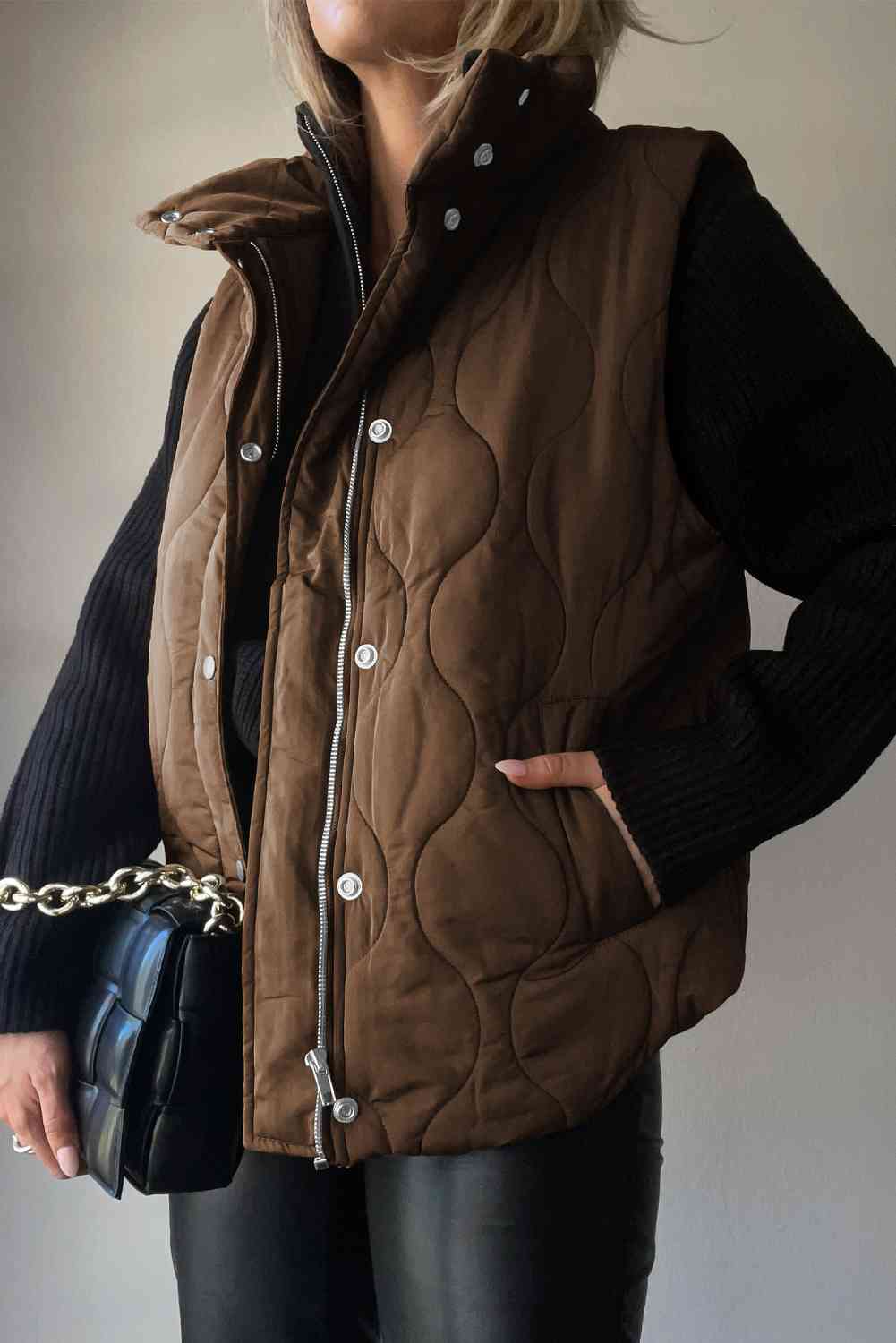 Trendy brown collared neck vest with pockets, paired with a black sweater and stylish handbag.