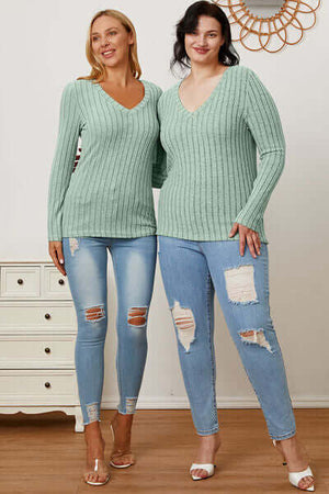 Two models wearing a ribbed v-neck long sleeve t-shirt in green, paired with distressed jeans.
