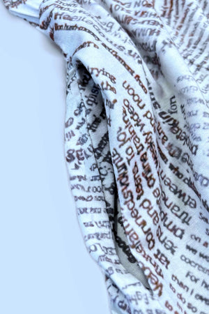 Close-up of fabric featuring a text print design in beige and brown colors.