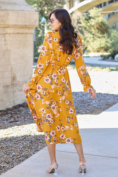 Back view of a woman wearing a floral tie-back flounce sleeve dress in mustard yellow, showcasing its elegant design.