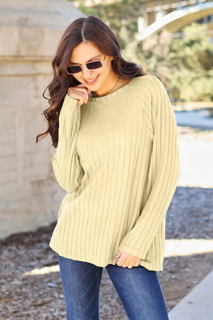 Model wearing a light green ribbed long sleeve knit top paired with jeans and sunglasses outdoors.