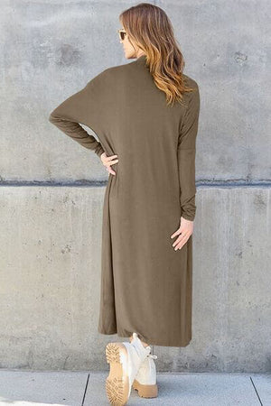 Back view of a woman in a long sleeve olive green cover-up dress with pockets and a relaxed fit.