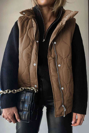 Collared neck vest with pockets, brown quilted design, styled with a black sweater and handbag.