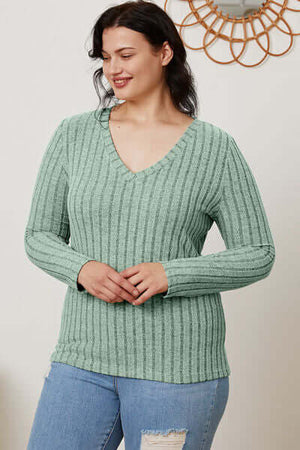 Model wearing a green ribbed V-neck long sleeve t-shirt, styled with casual jeans, showcasing a comfortable fit.