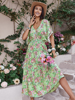 Smocked floral V-neck short sleeve dress in green with floral pattern, model smiling, holding bouquet, summer fashion.