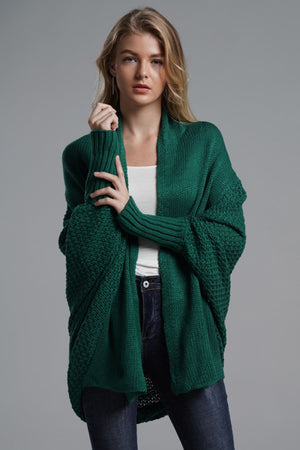 Woman wearing a green double take dolman sleeve open front cardigan in a studio setting.