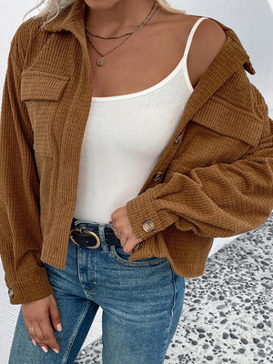 Woman in a collared neck button front jacket with pockets, layered over a white top and styled with blue jeans.