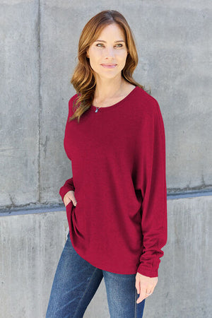 Woman wearing a burgundy long sleeve round neck t-shirt, showcasing casual style with a relaxed fit.