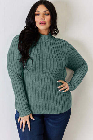 Model wearing a green ribbed mock neck long sleeve top paired with jeans, showcasing a stylish and comfortable look.