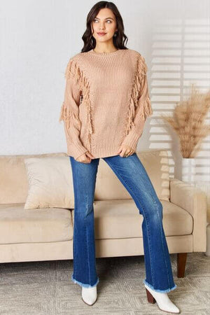 Stylish long sleeve sweater with tassel details paired with flared jeans, perfect for casual and dressy occasions.
