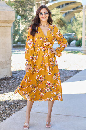 Model wearing a mustard floral tie back flounce sleeve dress in an outdoor setting, showcasing a stylish summer look.