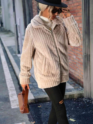 Woman in a zip-up collared ribbed jacket with pockets walking in a stylish urban setting.