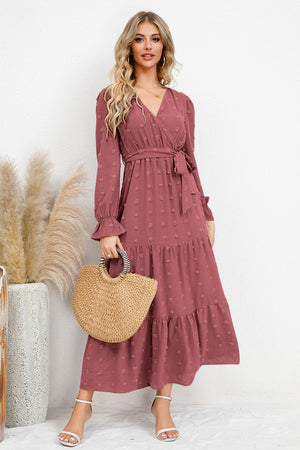 Model wearing a Swiss Dot Tied Surplice Flounce Sleeve Dress, styled with a straw bag on a light background.