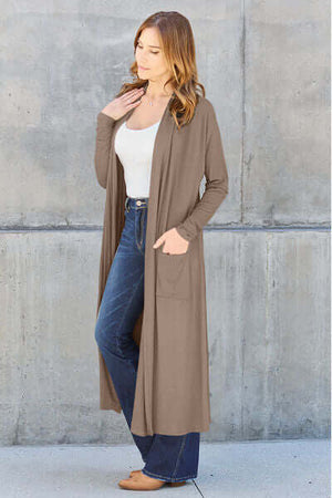Woman wearing Basic Bae open front long sleeve cover-up with pockets, styled with denim jeans and a white top.