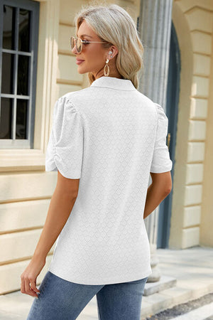 Stylish woman in white eyelet blouse with puff sleeves, paired with jeans, showcasing a chic summer look.
