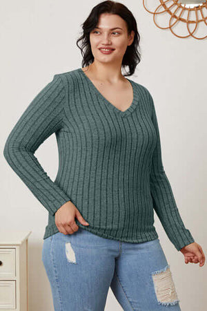 Model wearing a teal ribbed v-neck long sleeve t-shirt paired with jeans, showcasing a casual and stylish look.