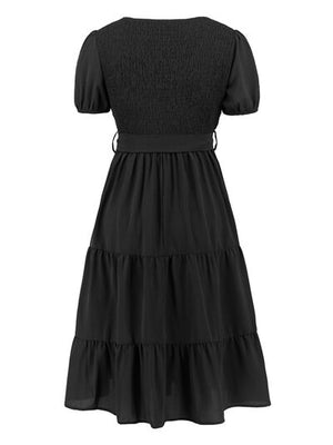 Back view of smocked tie front short sleeve tiered dress in black, featuring a flowy, layered skirt.