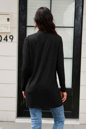 Back view of a woman wearing a long sleeve black cardigan with pockets, styled with blue jeans.