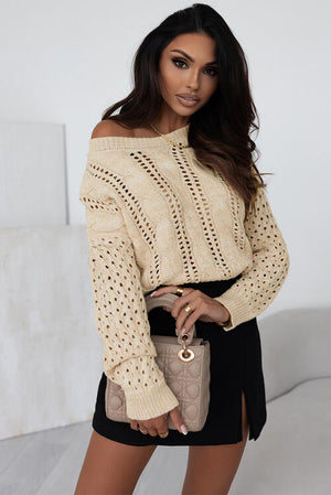 Stylish woman wearing a beige openwork cable-knit top paired with a black skirt and handbag.