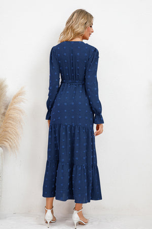 Back view of a navy Swiss Dot Tied Surplice Flounce Sleeve Dress, featuring long sleeves and a tiered skirt.