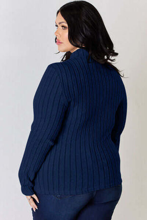 Model wearing a navy ribbed mock neck long sleeve sweater, viewed from the back, showcasing its stylish design.