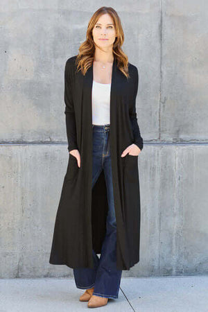 Model wearing Basic Bae Full Size Open Front Long Sleeve Cover Up in black with pockets, styled with flared jeans.