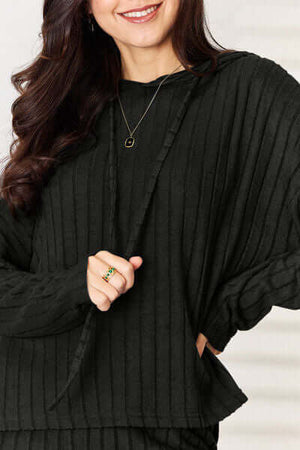 Close-up of a woman wearing a cozy black ribbed hooded top from the Basic Bae set, featuring a relaxed fit.