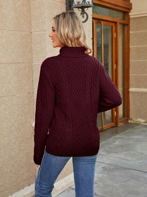 Back view of a woman wearing a burgundy cable-knit mock neck sweater paired with denim jeans.