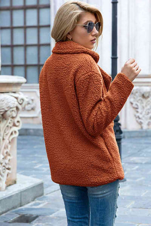 Woman wearing a full size lapel collar sherpa coat in orange, showcasing a cozy, casual urban style.