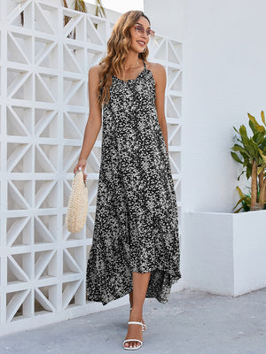 Elegant woman in a Ditsy Floral Scoop Neck Midi Cami Dress, styled with a bag and sunglasses, by a white wall.