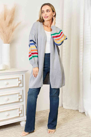 Model wearing a multicolored stripe open front longline cardigan with blue jeans, showcasing a cozy and stylish look.
