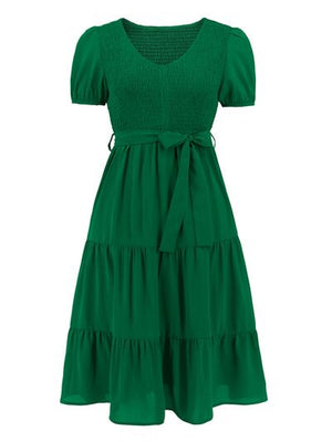 Green smocked tie front short sleeve tiered dress with a flattering silhouette and playful design.
