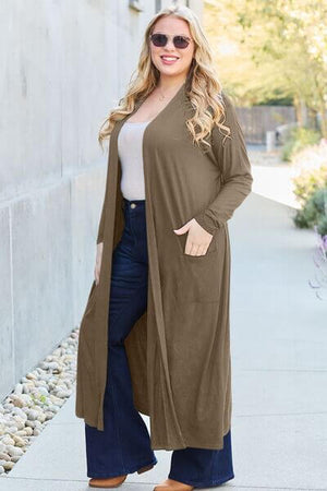 Woman wearing a Basic Bae full size open front long sleeve cover up with pockets, styled with flared jeans.
