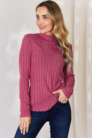 Model wearing a pink ribbed mock neck long sleeve t-shirt, styled with blue jeans against a light background.