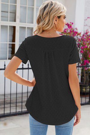 Back view of a woman in a black eyelet quarter button short sleeve t-shirt, showcasing elegant details and relaxed fit.