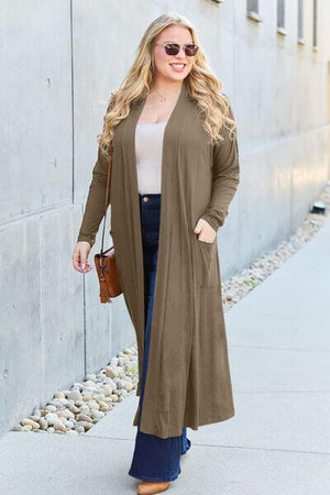 Model wearing Basic Bae Full Size Open Front Long Sleeve Cover Up in olive, paired with jeans and sunglasses.