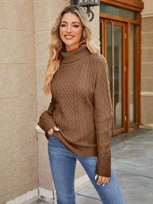 Model wearing a stylish cable-knit mock neck sweater in brown, paired with blue jeans, outdoors.