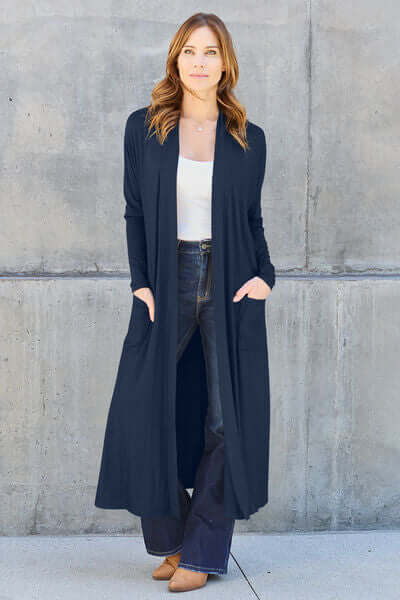 Model wearing a navy Basic Bae full size open front long sleeve cover up with pockets, paired with a white top and jeans.