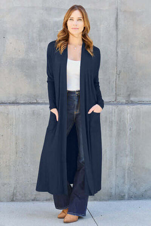 Model wearing a navy Basic Bae full size open front long sleeve cover up with pockets, paired with a white top and jeans.