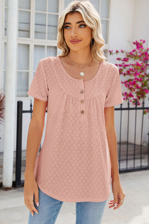 Woman wearing a pink eyelet quarter button short sleeve T-shirt, featuring a relaxed fit and decorative buttons.