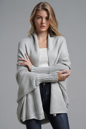Model wearing a light grey dolman sleeve open front ribbed cardigan, styled with a white tank and jeans.