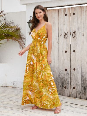 Model wearing a printed surplice spaghetti strap dress with a vibrant yellow and green palm leaf design.