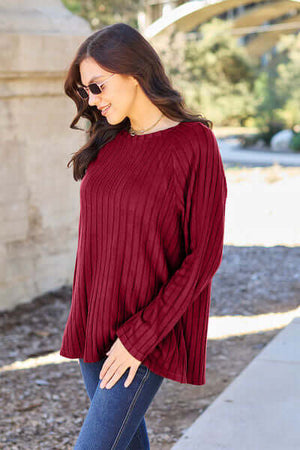 Model wearing a burgundy ribbed long sleeve knit top, showcasing a relaxed fit and stylish design.